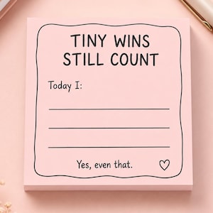 以下が含まれることがあります： 黒い波状の枠線と上部に「TINY WINS STILL COUNT」というテキストが印刷された、正方形の薄いピンク色の付箋メモ帳。その下には「Today I:」という見出しと記入用の3本の横線があり、最後に「Yes, even that.」という言葉とハートのマークが描かれています。