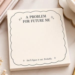 May include: A square notepad with cream-colored paper featuring a black scalloped border. The text A PROBLEM FOR FUTURE ME is printed at the top with small star icons, and She'll figure it out. Probably. is printed at the bottom.