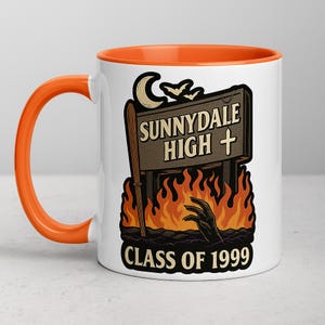 Peut inclure: Mug en céramique blanche avec intérieur et anse orange. Le mug présente un graphisme avec un panneau indiquant "Sunnydale High" avec une croix, des chauves-souris et une lune. Des flammes et une main sortant du sol sont en dessous, avec "Class of 1999" en bas.