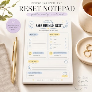 May include: A 4x6 personalized notepad titled Bare Minimum Reset with sections for must do, body check, home task, responsibility, and gentle things. The white paper features blue and yellow accents, heart icons, and text prompts for daily tasks.