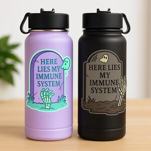 Sticker comparison mockup showing pastel cute glow sticker on lavender bottle and dark gothic sticker on black bottle. Both feature humorous tombstone design that says Here Lies My Immune System. Spoonie gift idea.