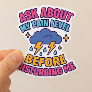 May include: A sticker with the text "ASK ABOUT MY PAIN LEVEL BEFORE DISTURBING ME." The design features a blue cloud with lightning bolts, raindrops, and star accents. The text is in pink, blue, and yellow.