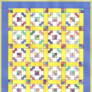 May include: A yellow and blue quilt with a patchwork design. The quilt is made up of small squares of fabric in various colours and patterns. The quilt is bordered by a blue fabric with white polka dots.
