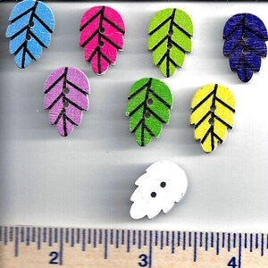 Puede incluir: Surtido de ocho botones de madera con forma de hoja en varios colores, incluyendo azul, rosa, verde, amarillo y blanco. Cada botón tiene un contorno negro y dos agujeros.