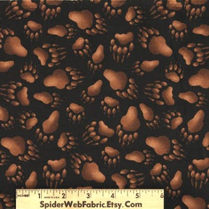 May include: Black fabric with a repeating pattern of brown bear paw prints. The paw prints vary in size and are scattered across the fabric. The text "SpiderWebFabric.Etsy.Com" is visible at the bottom.