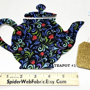 May include: A fabric teapot cutout with a black background and a colorful floral design. The teapot is accompanied by a tea bag cutout. A ruler shows the teapot is approximately 6 inches long. The text "TEAPOT #1" is visible.