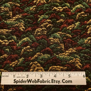 May include: Fabric with a dense forest pattern in shades of green, red, and yellow. A wooden ruler with inch markings is at the bottom. The text "SpiderWebFabric.Etsy.Com" is printed on the ruler.