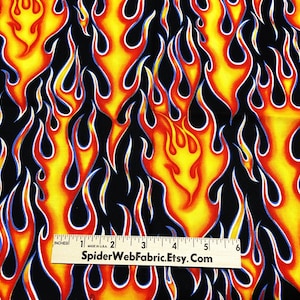Può includere: Tessuto nero con un motivo ripetuto di fiamme gialle, arancioni e rosse. Un righello è incluso nell'immagine per la scala. Il righello indica "SpiderWebFabric.Etsy.com".