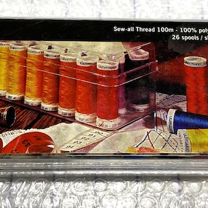 May include: A clear plastic box containing 26 spools of Gütermann Sew-all Thread. The spools are 100% polyester and come in a variety of colors. The box has a label that reads "Sew-all Thread 100m 100% polyester 26 spools/shades Sewing Thread Box Gütermann."