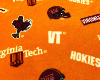 Puede incluir: Tela naranja con logotipos, cascos y texto de los Hokies de Virginia Tech. El diseño incluye las palabras "Virginia Tech" y "Hokies" en blanco, junto con el logotipo de VT y una mascota de pavo marrón. Una regla muestra pulgadas.