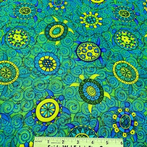 Puede incluir: Tela con un patrón repetido de tortugas estilizadas en tonos azules, verdes y amarillos. Las tortugas están rodeadas de diseños ondulados en espiral. Una regla muestra las medidas en pulgadas.
