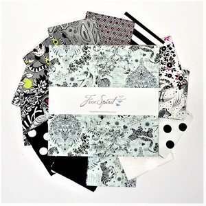 May include: A set of 12 black and white fabric squares with various patterns, including zebra stripes, polka dots, and floral designs. The fabric squares are arranged in a circle around a white card with the text "Free Spirit" printed on it.