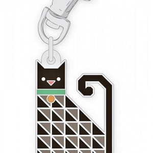 Può includere: Un portachiavi a forma di gatto nero con un motivo geometrico, un collare verde e un moschettone argentato. Il gatto è seduto con la coda arrotolata.