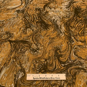May include: Abstract fabric with a swirling pattern in shades of brown, black, and white. The fabric has a marbled look and is perfect for quilting, crafts, and home decor projects.