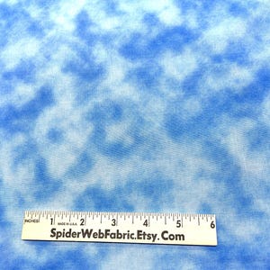 May include: A close-up of a blue and white tie-dye fabric with a ruler measuring 6 inches. The fabric has a cloudy, mottled pattern.