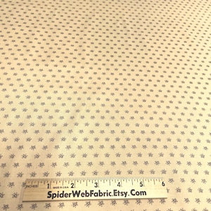 Puede incluir: Tela de color crema con un patrón repetido de pequeños diseños florales azul oscuro. Una regla de madera con medidas en pulgadas está colocada sobre la tela. El texto "SpiderWebFabric.Etsy.com" está impreso en la regla.