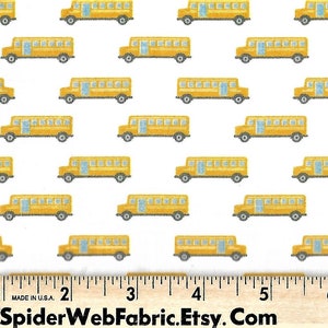 May include: White fabric with a repeating pattern of yellow school buses. The fabric is measured with a ruler in inches.