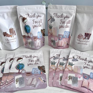 Puede incluir: Bolsas blancas con ilustraciones de acuarela y texto. Las bolsas presentan ilustraciones de un escritorio con un globo terráqueo, libros y una lámpara. El texto en las bolsas dice "Thank you for all you do!" y "Fully accomplish your ministry."