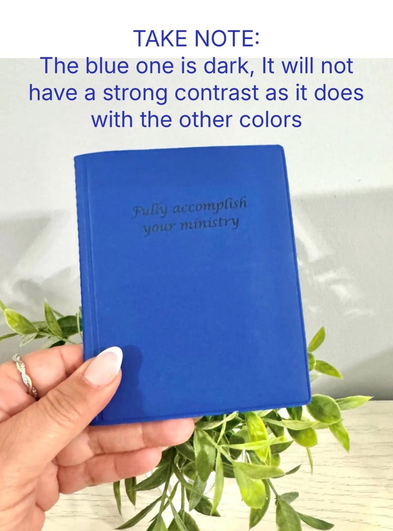 May include: A cobalt blue notebook with the text "Fully accomplish your ministry" is held in a hand. The notebook is surrounded by green foliage. The text "TAKE NOTE: The blue one is dark, It will not have a strong contrast as it does with the other colors" is at the top.
