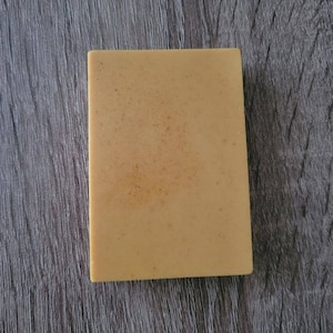 May include: A rectangular bar of soap with a light brown color and a slightly grainy texture.