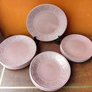 Può includere: Set di sei piatti piani in ceramica rosa con un bordo decorativo. I piatti hanno un design in rilievo attorno al bordo.