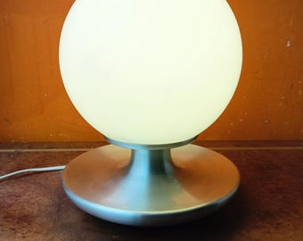 May include: A silver table lamp with a large white glass globe shade. The lamp has a round base and a cord.