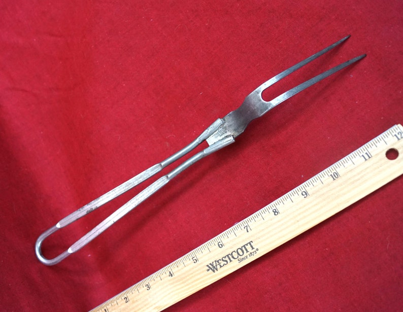 May include: A silver metal grilling fork with a long handle and two prongs. The fork is about 12 inches long and has a loop at the end of the handle.