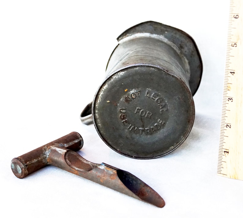 May include: A vintage metal oil can with a spout and a handle. The can is labeled "Not Legal For Use In Trade".