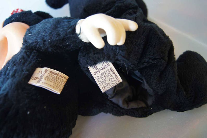 May include: Black plush Mickey Mouse puppet with a white glove hand. The puppet has two tags that say "Applause" on them.