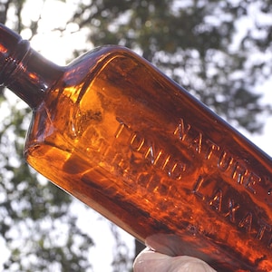 May include: A brown glass bottle with a label that reads "Nature's Tonic Laxative".