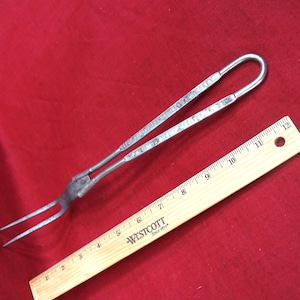 May include: A silver metal fork with a long handle and two prongs. The handle has a loop at the end and is marked with the text "PAT. JULY 17, 1906".