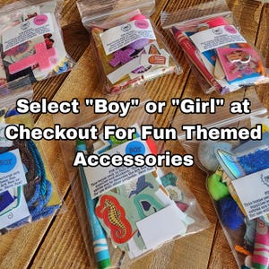 May include: Six clear plastic bags containing assorted craft supplies, including stickers, crayons, and decorative shapes. Each bag features a label marked with either Boy or Girl. The text Select Boy or Girl at Checkout For Fun Themed Accessories is overlaid.