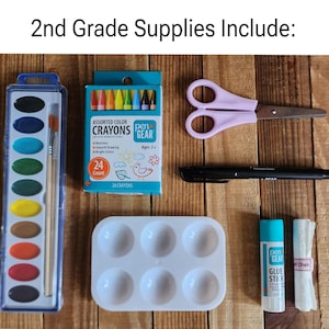 Może przedstawiać: Zestaw materiał&oacute;w szkolnych dla klasy 2, w tym zestaw akwareli, kredki, nożyczki, marker, paleta do malowania, sztyft kleju i kreda. Tekst "2nd Grade Supplies Include:" znajduje się u g&oacute;ry obrazu.