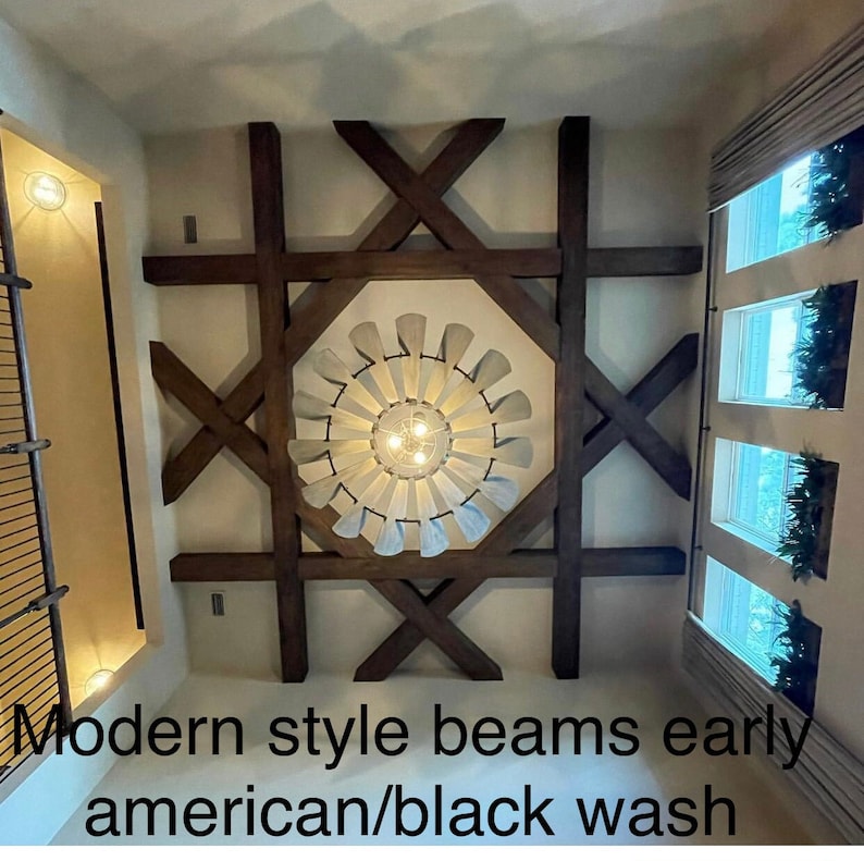 Op de afbeelding: Moderne houten balken in een kamer met een plafondventilator en ramen. De balken zijn donkerbruin gebeitst en hebben een zwarte wasbehandeling.