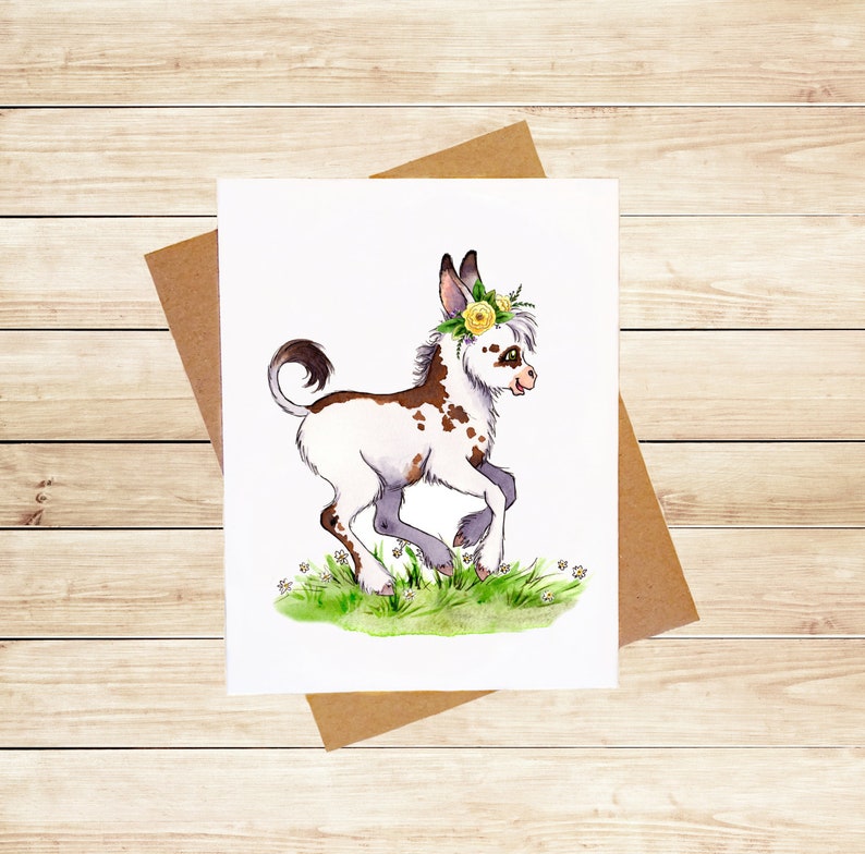 May include: A watercolor illustration of a white and brown spotted donkey with a yellow flower crown. The donkey is running through a field of green grass with white flowers.