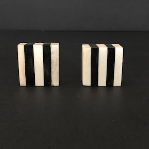 Könnte beinhalten: Zwei quadratische, schwarz-weiß gestreifte Dekorationsobjekte aus Knochen oder Holz.