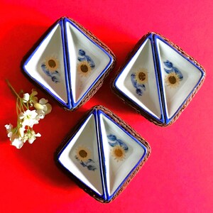 Puede incluir: Tres platos de cerámica divididos con diseños florales azules y blancos, colocados en cestas de mimbre marrón. Los platos son perfectos para servir pequeños aperitivos o salsas.