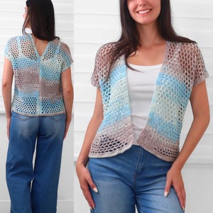 May include: A short-sleeved, open-front crochet cardigan featuring a variegated color pattern of light blue, turquoise, and soft brown. The garment is constructed with a loose, net-like stitch pattern and has a V-neckline, shown from both front and back.