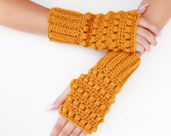 May include: A pair of mustard yellow fingerless gloves with a textured crochet design. The gloves are made with a bobble stitch.