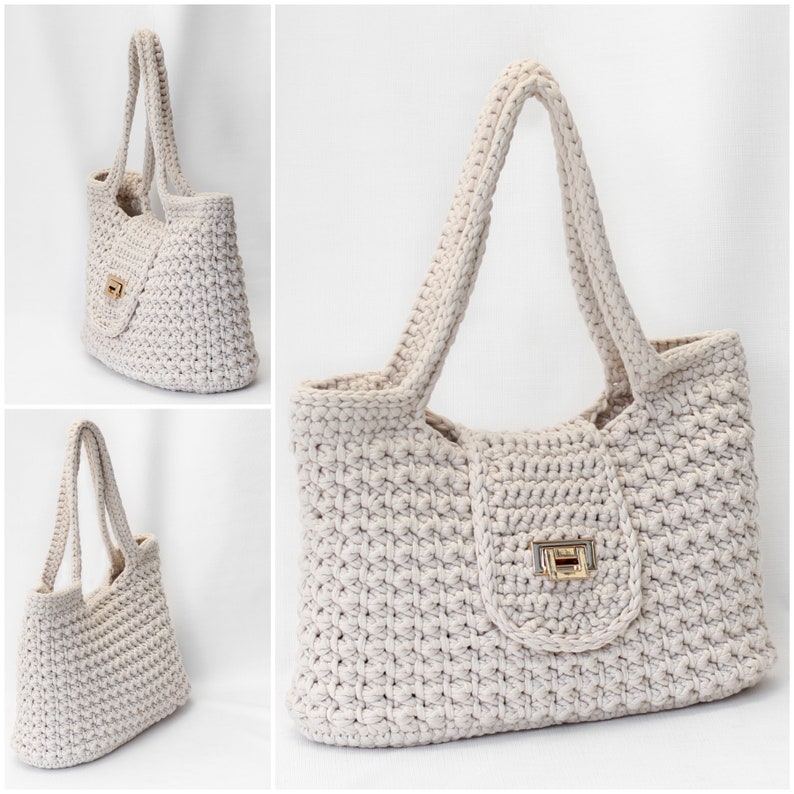 Puede incluir: Un bolso tote de crochet de color crema con cierre de solapa y cierre dorado. El bolso tiene dos asas largas.