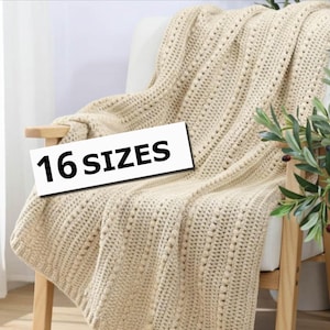 Pu&ograve; includere: Una coperta lavorata a maglia color crema drappeggiata su una sedia di legno. La coperta ha un motivo strutturato con piccoli fori distanziati. Il testo "16 SIZES" &egrave; visualizzato su un rettangolo bianco. Una pianta in vaso &egrave; visibile sullo sfondo.