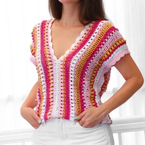 Pu&ograve; includere: Un top all'uncinetto fatto a mano e colorato con scollo a V. Il top presenta un motivo a righe nei toni del rosa, bianco e oro. Il lavoro all'uncinetto ha un bordo smerlato lungo lo scollo e le maniche. Il top &egrave; senza maniche.