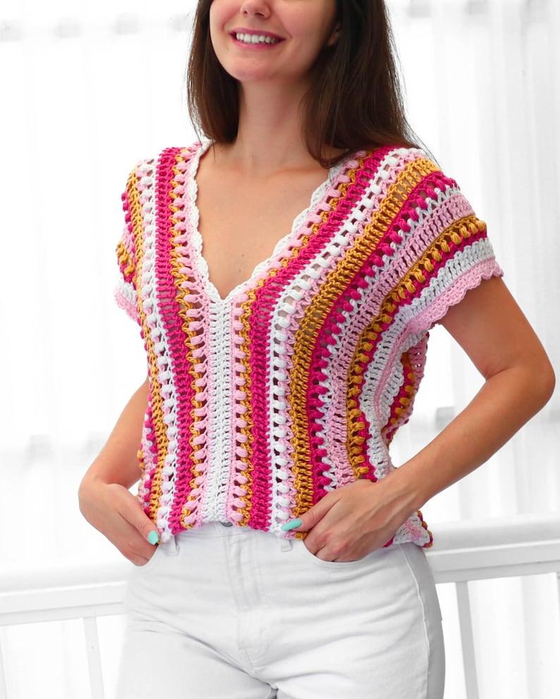 Pu&ograve; includere: Un top all'uncinetto fatto a mano e colorato con scollo a V. Il top presenta un motivo a righe nei toni del rosa, bianco e oro. Il lavoro all'uncinetto ha un bordo smerlato lungo lo scollo e le maniche. Il top &egrave; senza maniche.