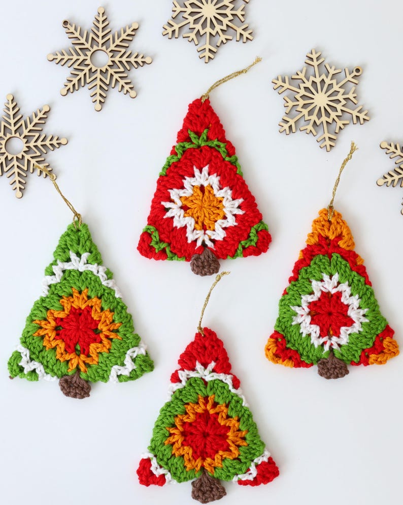 Puede incluir: Cinco adornos de &aacute;rbol de Navidad de ganchillo en rojo, verde, blanco, naranja y marr&oacute;n. Los adornos cuelgan de una cuerda dorada.