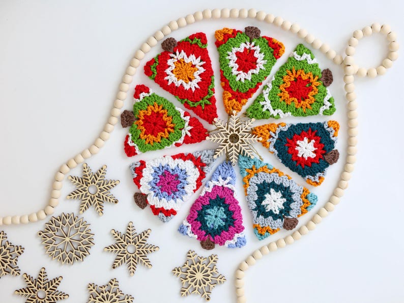 Puede incluir: Una colecci&oacute;n de adornos de &aacute;rbol de Navidad hechos a crochet en varios colores y patrones, incluyendo rojo, verde, azul y blanco. Los adornos est&aacute;n dispuestos en un c&iacute;rculo alrededor de una guirnalda de cuentas de madera.