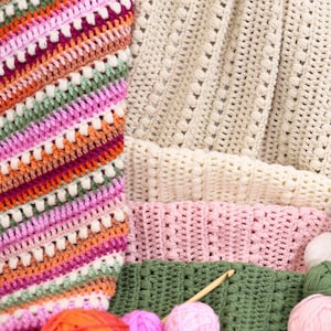 Pu&ograve; includere: Una collezione di articoli all'uncinetto colorati, tra cui coperte e gomitoli di lana. Le coperte presentano vari modelli di punti e combinazioni di colori, come arancione, rosa, verde e crema. Sono visibili anche diversi gomitoli di lana nei toni dell'arancione, del rosa e del verde.