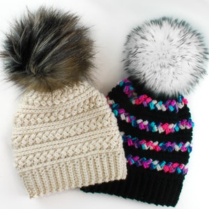 Puede incluir: Dos gorros de punto con pompones de piel sint&eacute;tica. Un gorro es crema con un pomp&oacute;n marr&oacute;n y el otro es negro con un pomp&oacute;n blanco y rayas de colores.