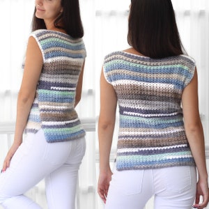 May include: A sleeveless crochet top with a striped pattern in shades of blue, green, white, and brown. The top has a boat neck and a relaxed fit.