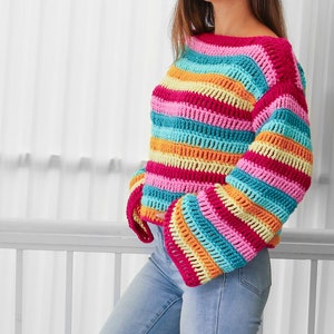 Peut inclure: Un haut en crochet ray&eacute; arc-en-ciel &agrave; manches longues et &agrave; col large. Le haut est fait de plusieurs couleurs, dont le rose, le bleu, le jaune et l'orange.
