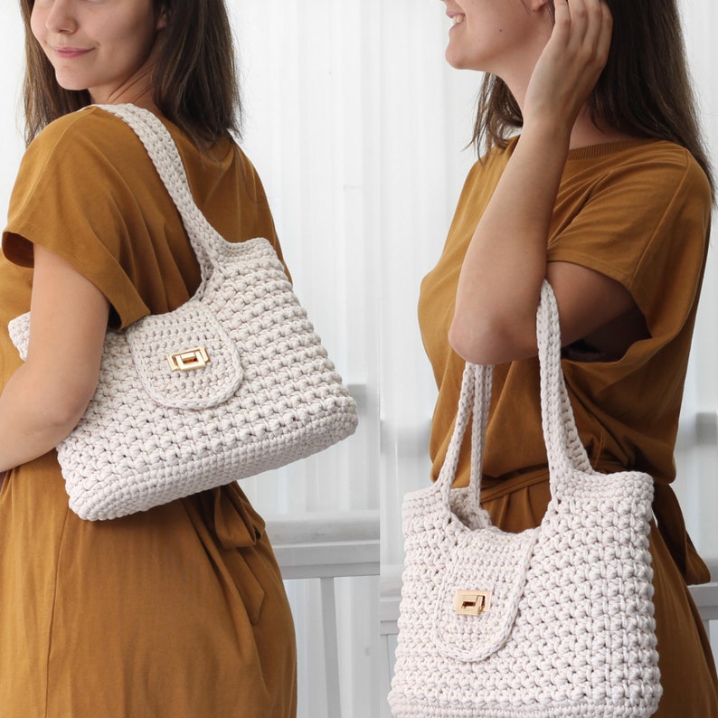 Puede incluir: Dos bolsos de mano de crochet blanco con cierre de broche dorado. Los bolsos tienen un dise&ntilde;o texturizado y tejido.